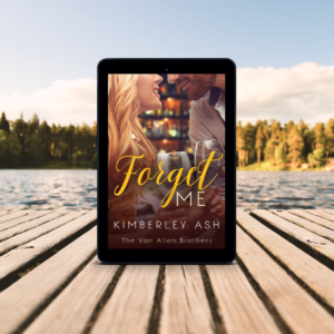 Wooden boardwalk with view of a lake and trees in the background, with a tablet showing the cover of Forget Me standing on the boardwalk.