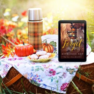 A fall picnic scene with a basket holding a plate of cookies, a pumpkin, a thermos covered with fall-colored plaid, and a tablet showing the cover of Forget Me.